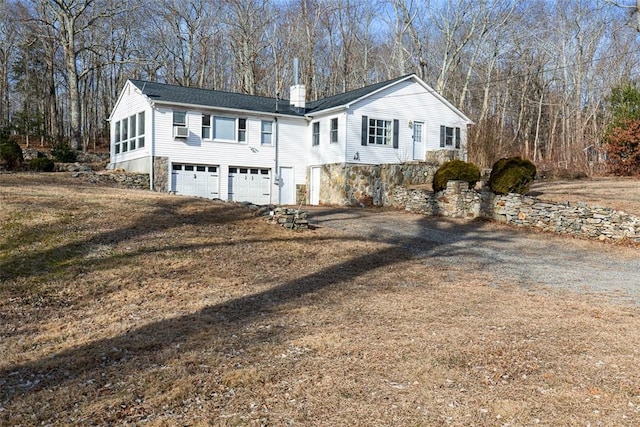 view of front of house featuring driveway, an attached garage, and a chimney