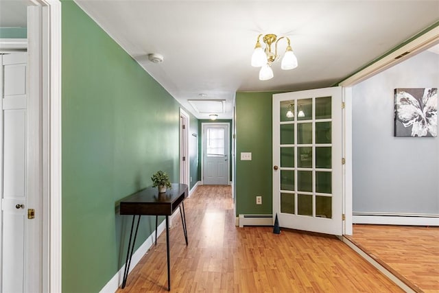 interior space with attic access, baseboards, light wood-type flooring, and a baseboard radiator