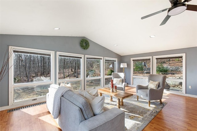 living area featuring visible vents, a ceiling fan, wood finished floors, baseboards, and lofted ceiling