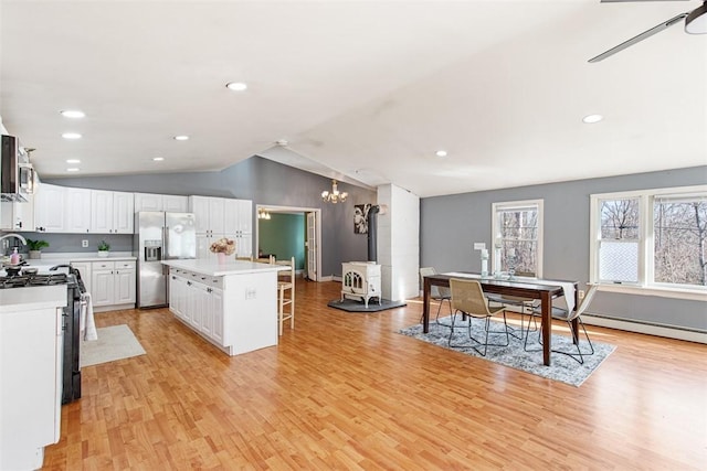 kitchen featuring a kitchen bar, black gas range, a center island, white cabinetry, and stainless steel fridge