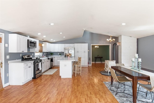 kitchen featuring a sink, stainless steel appliances, light countertops, a kitchen bar, and a notable chandelier