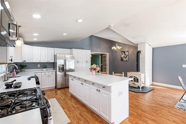 kitchen with a center island, stainless steel fridge with ice dispenser, vaulted ceiling, a wood stove, and an inviting chandelier