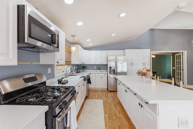 kitchen featuring light wood finished floors, a kitchen island, lofted ceiling, stainless steel appliances, and white cabinets