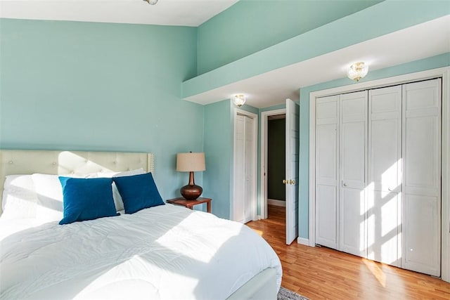 bedroom with light wood finished floors, two closets, and baseboards