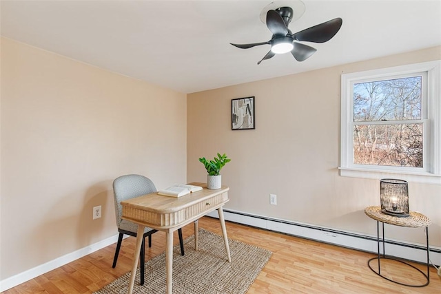 office area with ceiling fan, a baseboard heating unit, baseboards, and light wood-style flooring