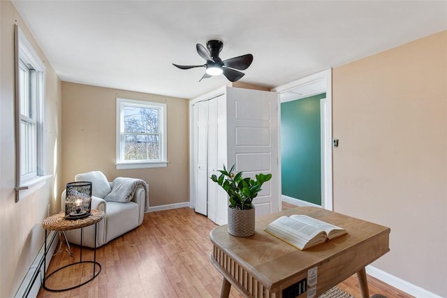 interior space featuring light wood-style flooring, baseboards, baseboard heating, and ceiling fan