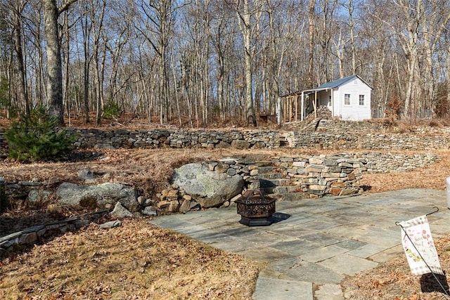 view of patio / terrace featuring a fire pit and a view of trees