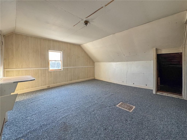 additional living space with vaulted ceiling, carpet flooring, baseboards, and visible vents