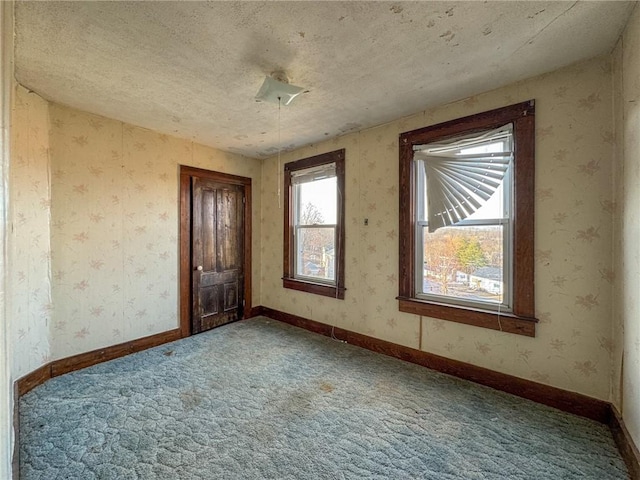 carpeted empty room featuring baseboards and wallpapered walls