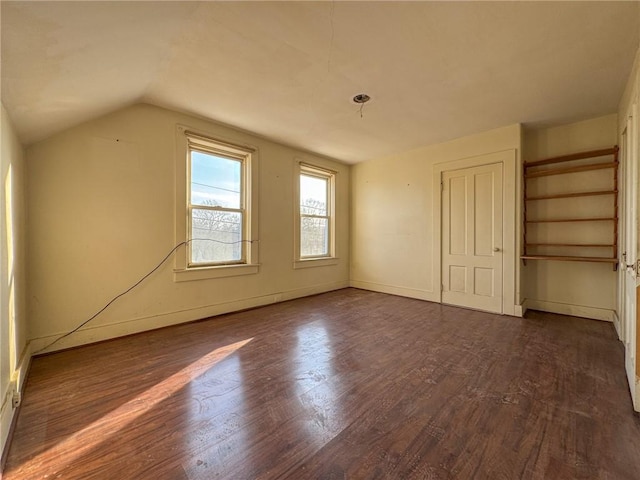 unfurnished bedroom with dark wood-style floors, baseboards, and lofted ceiling