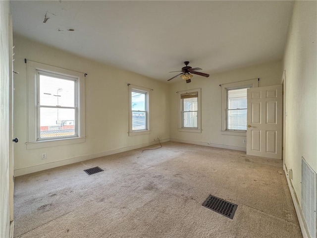 unfurnished room featuring plenty of natural light, a ceiling fan, and visible vents