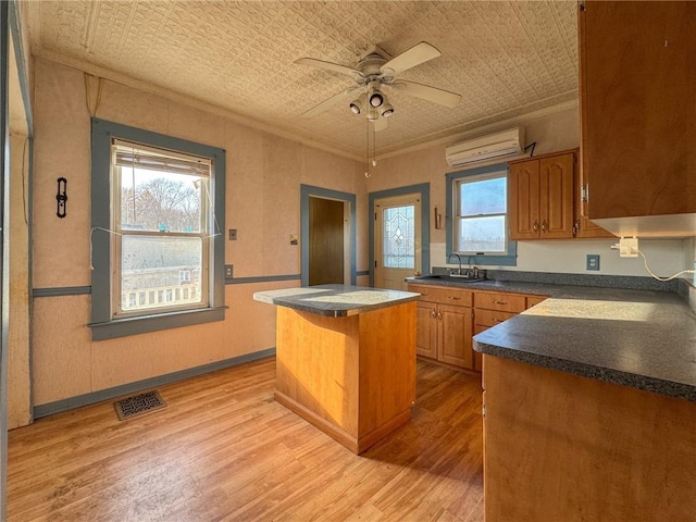 kitchen with visible vents, a kitchen island, a wall mounted AC, an ornate ceiling, and a sink