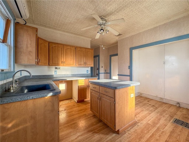 kitchen featuring a kitchen island, a wall unit AC, light wood-style floors, an ornate ceiling, and a sink