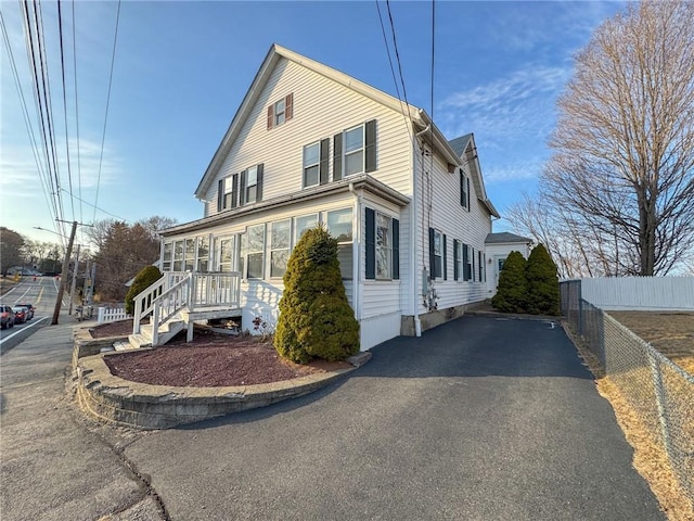 view of front of home featuring a sunroom, driveway, and fence