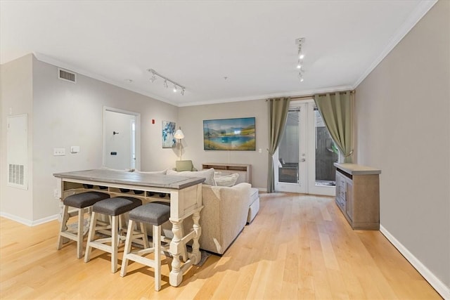 living room featuring visible vents, baseboards, crown molding, and light wood-style floors