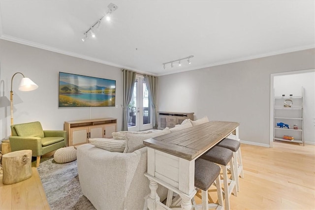 living room featuring light wood-type flooring, baseboards, and ornamental molding