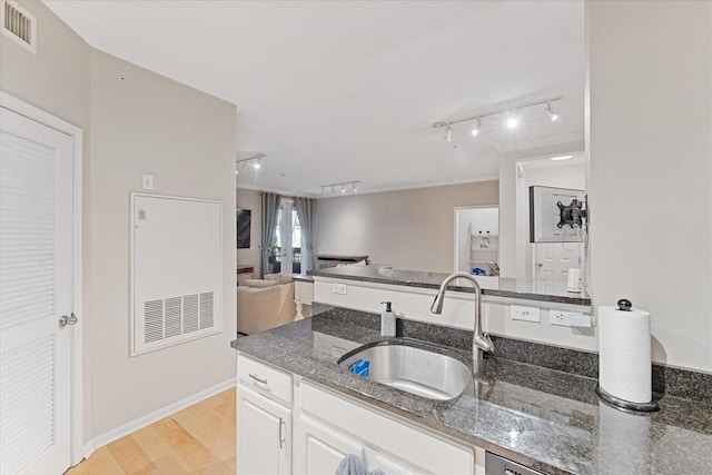 kitchen featuring visible vents, open floor plan, dark stone countertops, white cabinets, and a sink