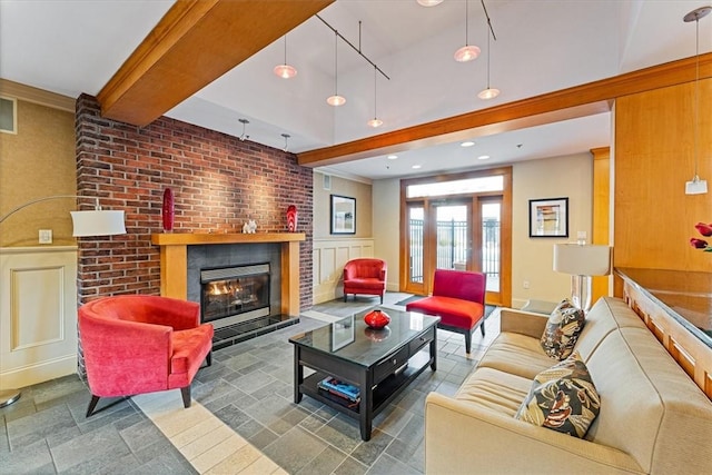 living room with stone tile flooring, beam ceiling, a fireplace, and baseboards