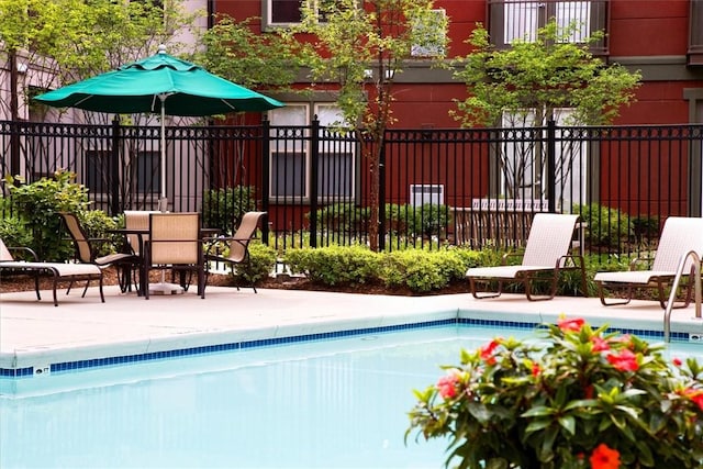 community pool with a patio and fence