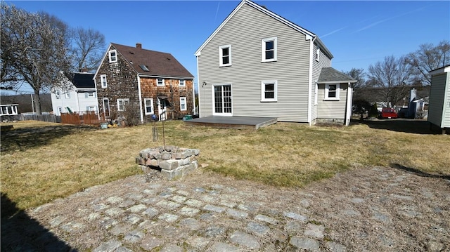 back of property with a deck, a lawn, and an outdoor fire pit