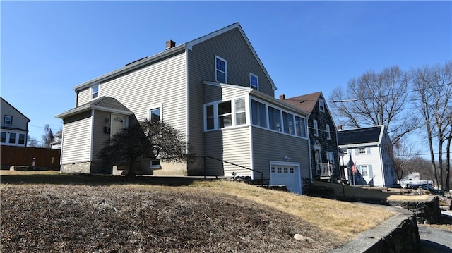 view of side of property featuring a chimney and a garage