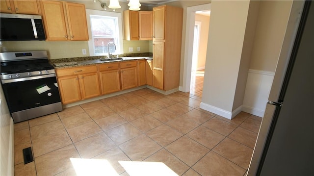 kitchen with light tile patterned floors, baseboards, a sink, appliances with stainless steel finishes, and backsplash