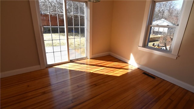 spare room with visible vents, baseboards, and hardwood / wood-style floors