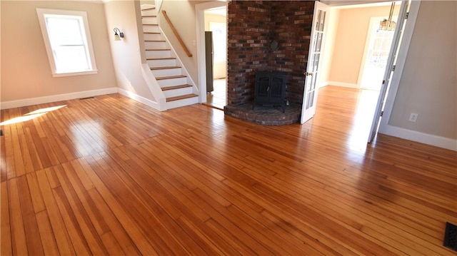 unfurnished living room featuring stairway, wood-type flooring, and baseboards