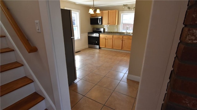 kitchen with light brown cabinetry, light tile patterned floors, appliances with stainless steel finishes, and a sink