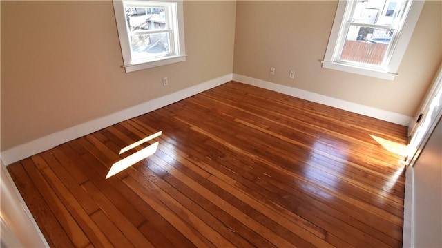 spare room with plenty of natural light, baseboards, and hardwood / wood-style flooring