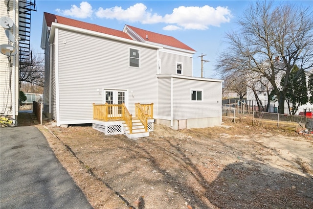 back of property with french doors, aphalt driveway, a deck, and fence