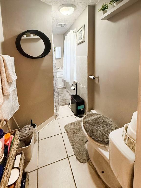 bathroom with tile patterned floors, toilet, visible vents, and a textured ceiling