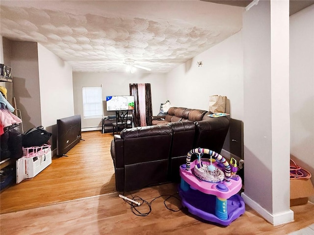 living area with baseboards, a textured ceiling, ceiling fan, and wood finished floors