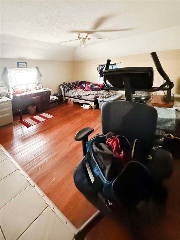 bedroom featuring a ceiling fan, wood finished floors, and a textured ceiling