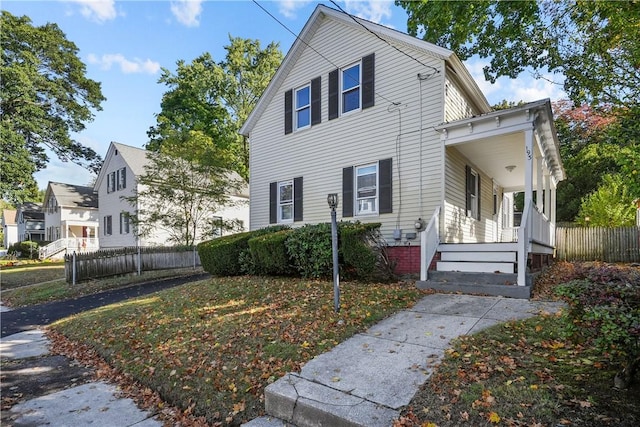 view of side of property featuring a porch and fence