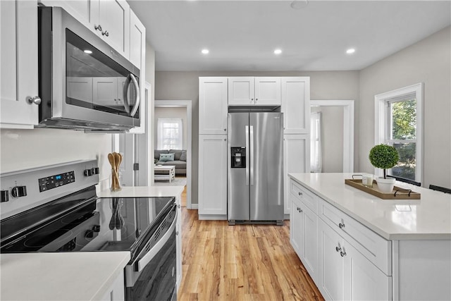 kitchen featuring light wood-type flooring, appliances with stainless steel finishes, white cabinets, and light countertops