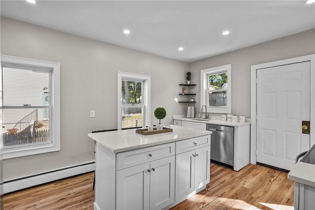 kitchen featuring a baseboard heating unit, light countertops, stainless steel dishwasher, light wood-style floors, and a sink