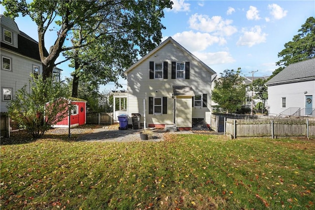 back of house featuring an outbuilding, a shed, a yard, and fence