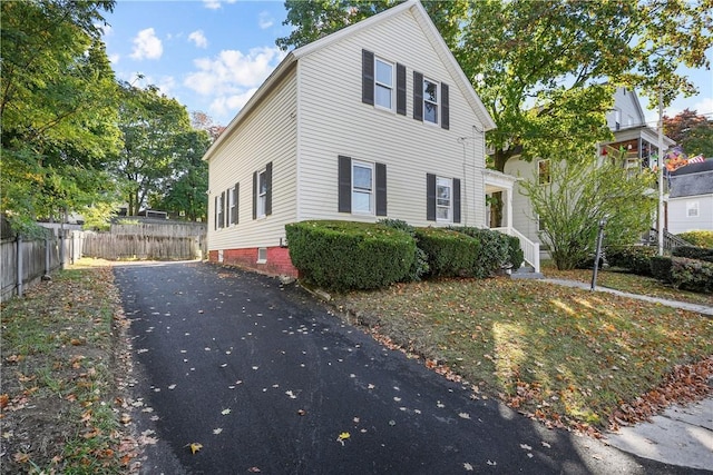 view of front facade featuring driveway and fence