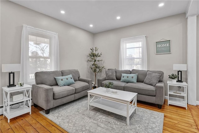 living room with a baseboard heating unit, recessed lighting, and light wood-type flooring