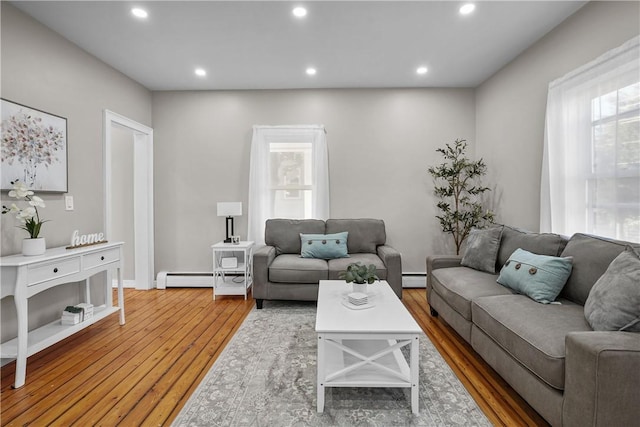 living area with recessed lighting, a baseboard heating unit, and wood finished floors