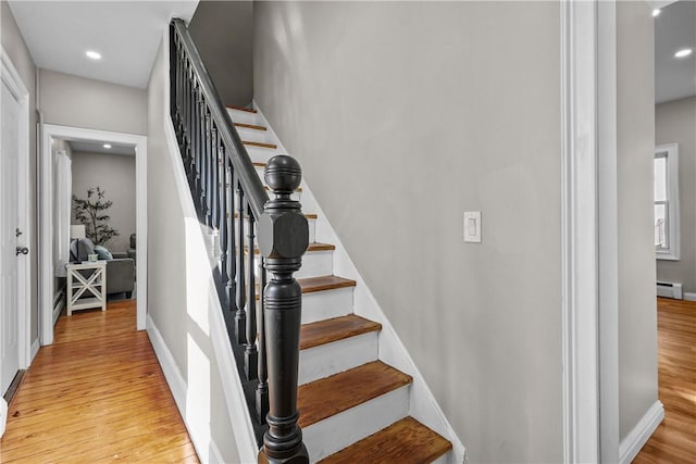 stairway featuring recessed lighting, baseboards, baseboard heating, and wood finished floors