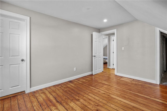 unfurnished bedroom featuring vaulted ceiling, baseboards, and light wood-type flooring