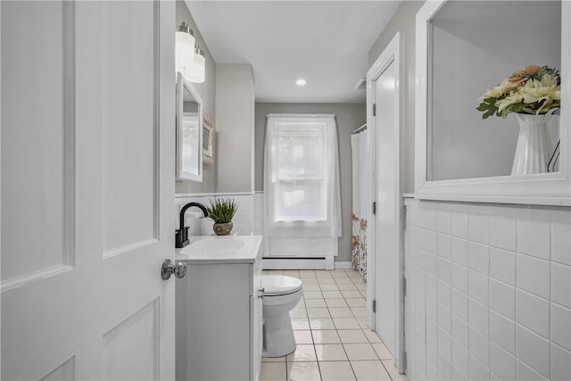 bathroom with vanity, tile patterned flooring, a baseboard heating unit, tile walls, and toilet