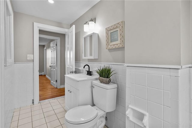 half bath with a baseboard radiator, toilet, tile walls, and tile patterned flooring