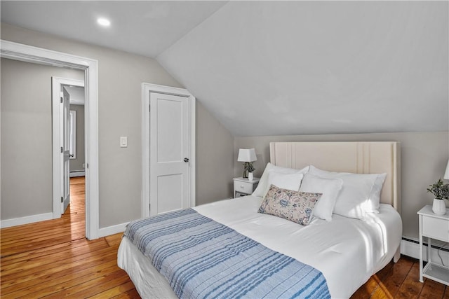 bedroom with baseboards, lofted ceiling, and hardwood / wood-style floors