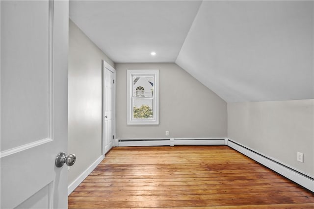 bonus room with baseboard heating, light wood-type flooring, and lofted ceiling