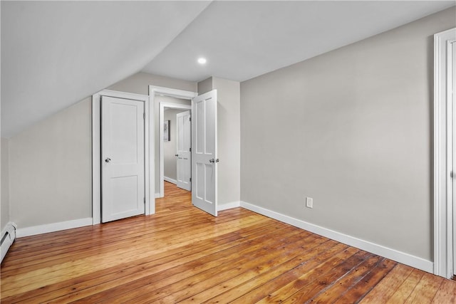 unfurnished bedroom featuring light wood-type flooring, baseboards, lofted ceiling, and a baseboard radiator