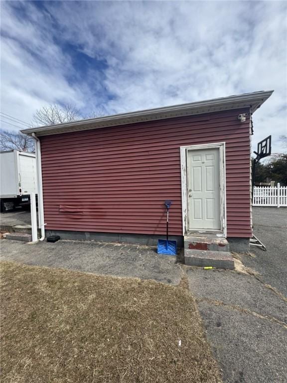 view of outbuilding featuring entry steps and fence