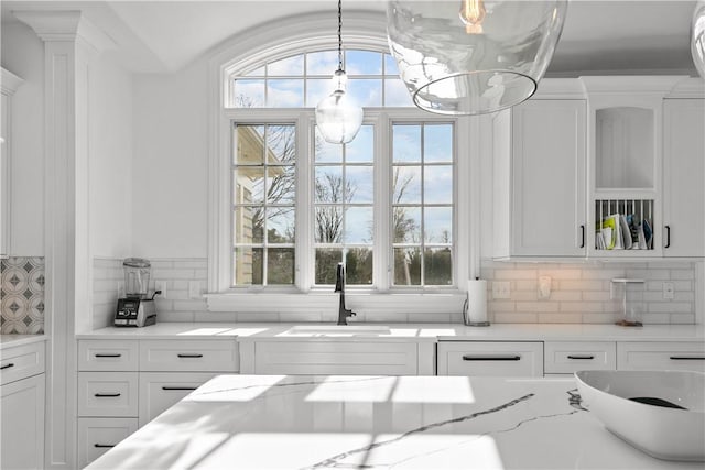 50 Kenyon Ave, East Greenwich, RI 02818 - kitchen featuring a healthy amount of sunlight, white cabinets, a sink, and tasteful backsplash